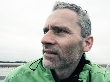 Close-up of mature man looking away against sky