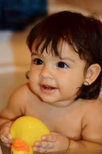 Close-up of cute baby girl playing with rubber duck while bathing in bathtub