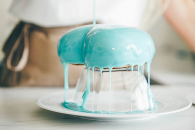 Close up woman decorating cake with glaze.