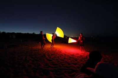 People on beach against clear sky at sunset