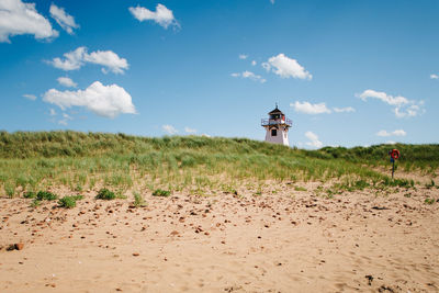 Lighthouse in distance on shore against the sky