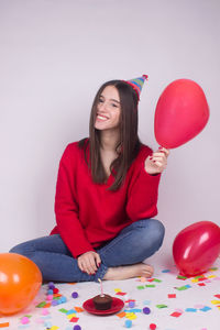 Smiling young woman sitting with balloons