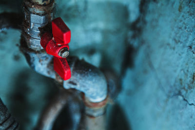 Old rusty water pipes with counters and red valves covered with aged chapped mint-green color paint