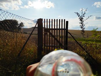 Metal fence on field against sky