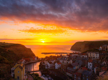 Aerial view of townscape by sea against romantic sky