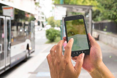 Cropped hand of woman using mobile phone outdoors