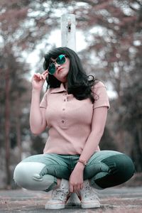 Full length of young woman crouching on field