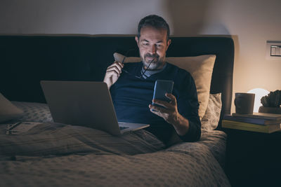 Man works with laptop lying on bed. male home working remote office sitting in bedroom use devices