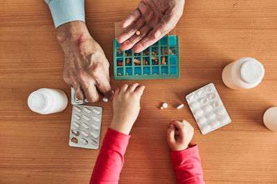 Grandchild helping grandfather to organize medication into pill dispenser. senior man routine