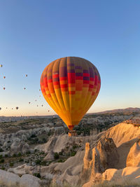 Hot air balloon flying over rocks against clear sky