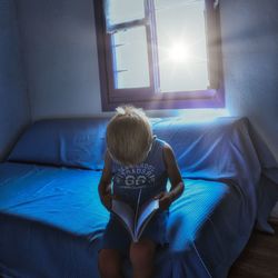 Rear view of boy sitting on sofa at home