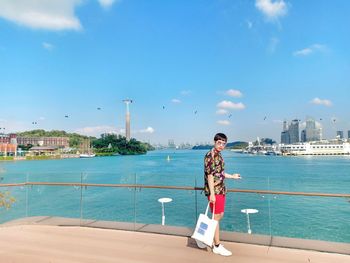 Rear view of woman standing by sea against sky