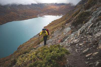 Man climbing on mountain against lake