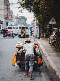 Rear view of man walking on street in city