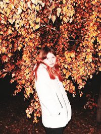 Portrait of woman standing against plant during autumn at night