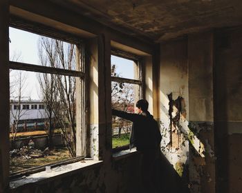 Man standing in front of window in abandoned house