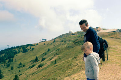 Side view of a boy standing on landscape against sky