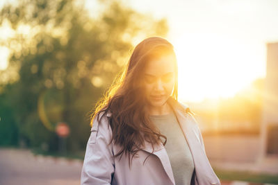 Beautiful girl with long hair in a grey trench coat outdoors on the street spring