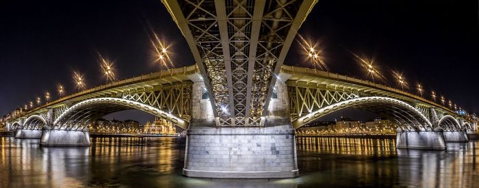 Illuminated bridge over river in city at night