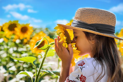 Cute girl smelling sunflower on field