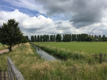 Scenic view of grassy field against cloudy sky