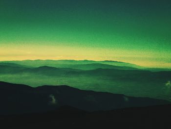 Silhouette landscape against mountain range during sunrise