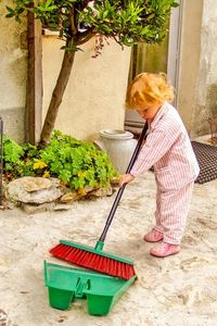 Full length of girl cleaning yard with broom