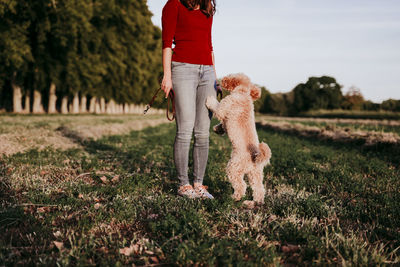 Low section of woman standing with dog on land