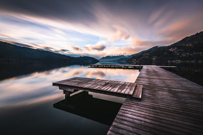 Pier over lake against sky during sunset