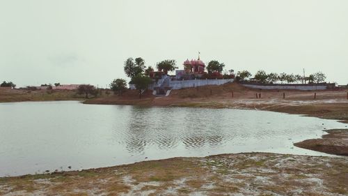 Scenic view of river by building against clear sky