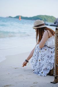 Side view of woman sitting at beach