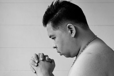 Portrait of young man looking away against wall