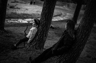 People sitting on tree trunk by field