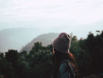 Rear view of woman by trees against sky