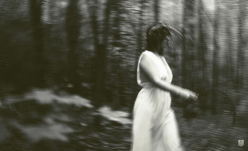 Blurred motion of woman standing by lake