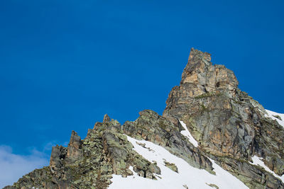 Low angle view of snowcapped mountain against blue sky