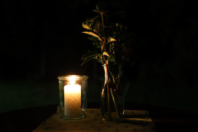 Illuminated tea light candles on table in dark room