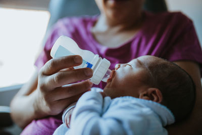 Midsection of mother feeding baby with bottle