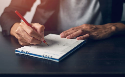 Midsection of man reading book on table