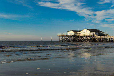 House on beach by sea against sky