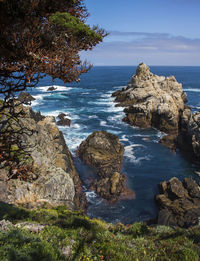 Scenic view of rocks by sea against sky