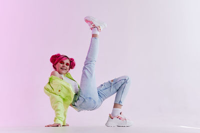 Low angle view of woman with arms raised against white background