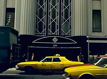 Yellow car on street against buildings in city