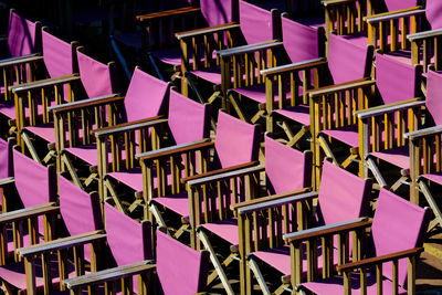 Rows of empty purple folding cancass chairs viewed from above.