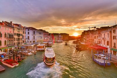 Boats moored in canal against buildings during sunset