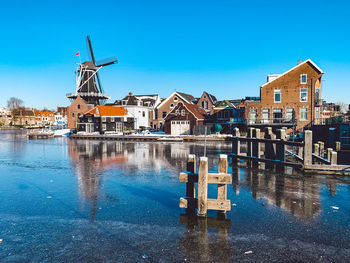 Canal amidst buildings against blue sky