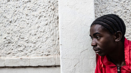 Portrait of young man standing against wall