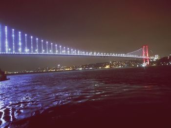 Illuminated bridge over sea at night