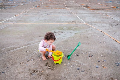 High angle view of baby girl playing with toy at beach