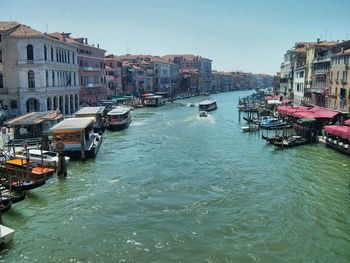 Boats moored in canal amidst buildings in city against sky